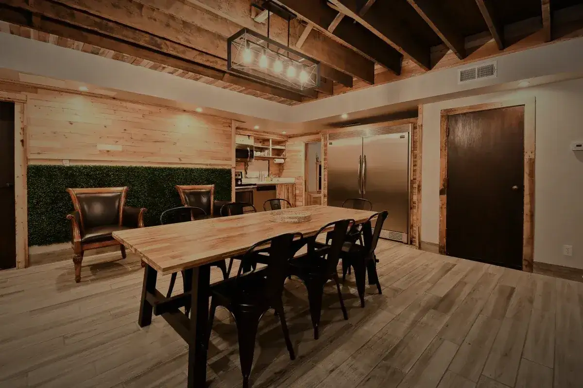 The communal table under exposed timber beams, a living wall behind it.