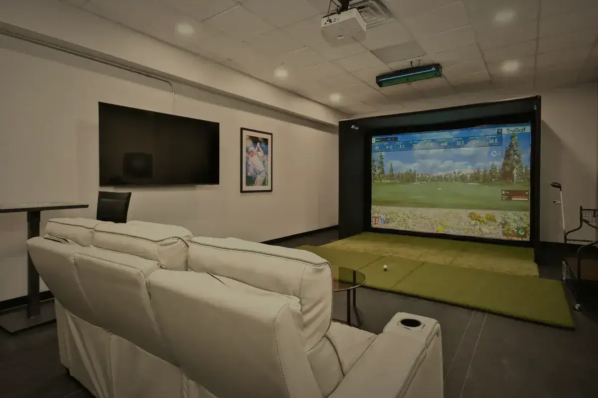 The golf simulator seen across the seating, the screen lit.