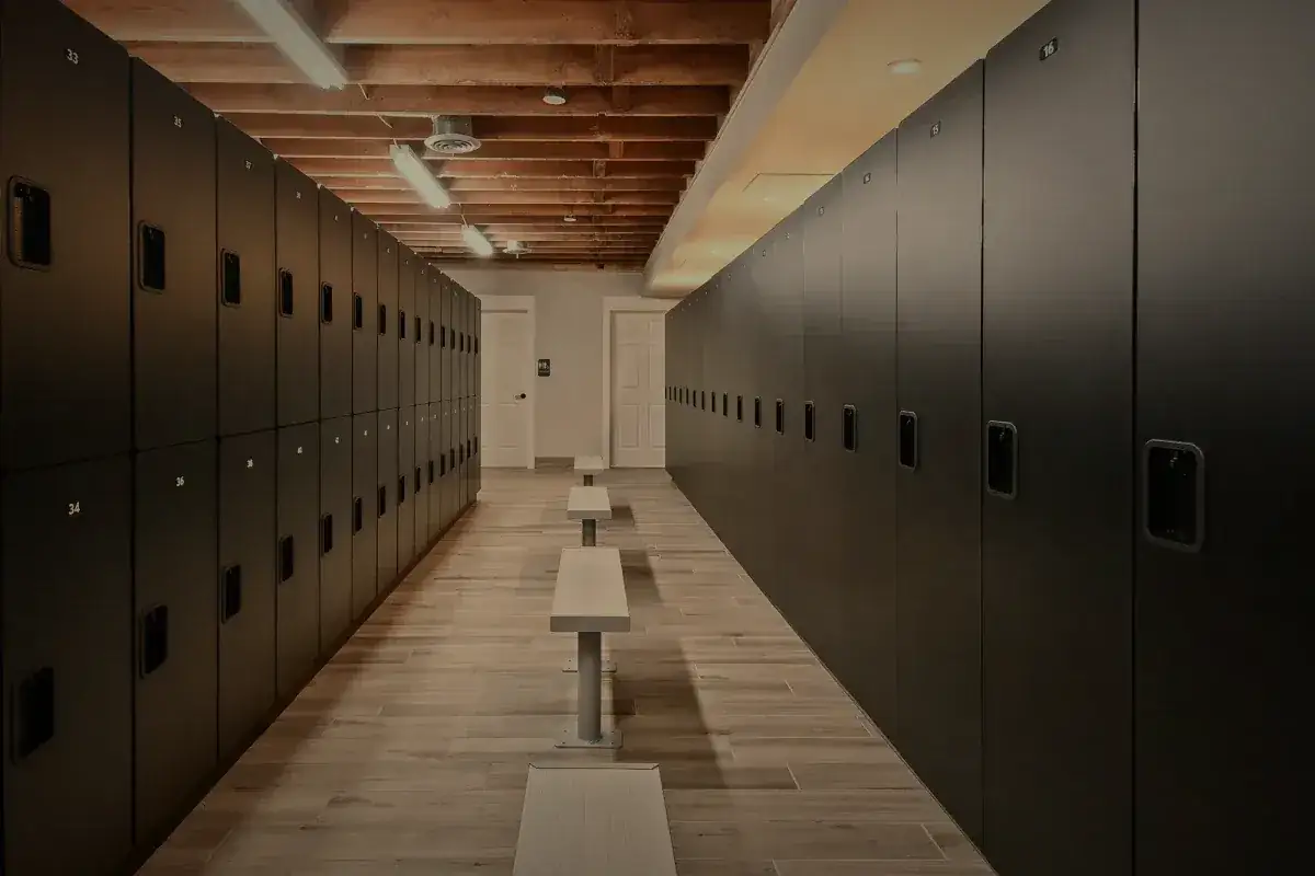 The locker corridor, benches down the center under timber.