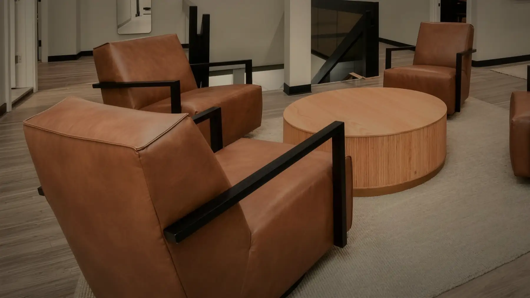 The lounge at Opus, four leather chairs around a round oak table.